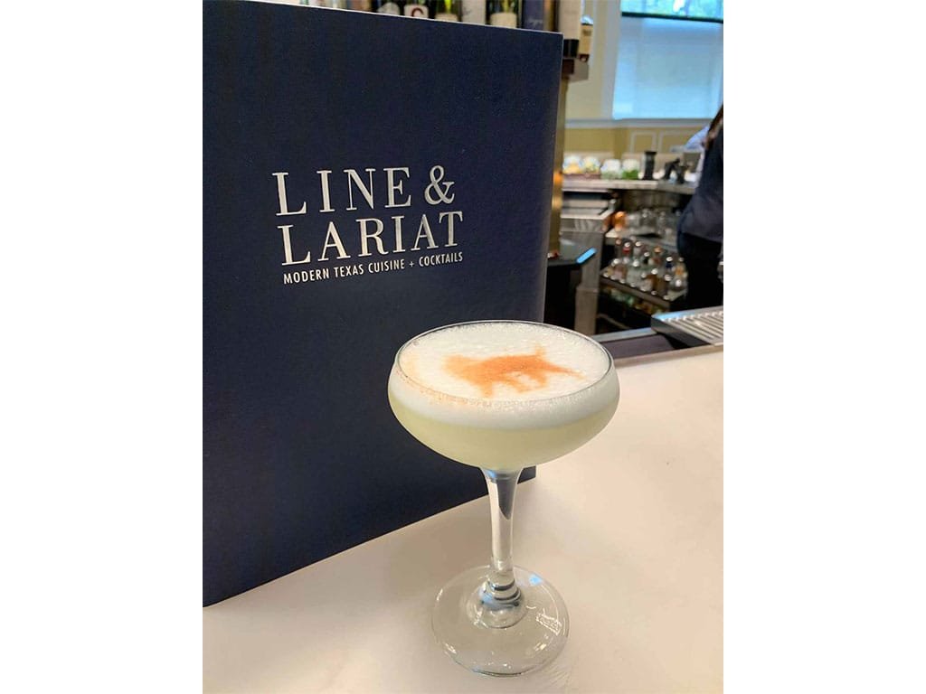 Navy Line and Lariat menu cover behind a frothy cocktail
